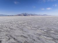 there is a lone motorcycle parked in the desert, with mountains in the background, and no one on the side