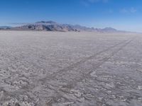 there is a lone motorcycle parked in the desert, with mountains in the background, and no one on the side