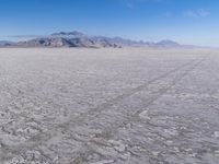 there is a lone motorcycle parked in the desert, with mountains in the background, and no one on the side