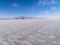 there is a lone motorcycle parked in the desert, with mountains in the background, and no one on the side