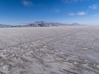 there is a lone motorcycle parked in the desert, with mountains in the background, and no one on the side