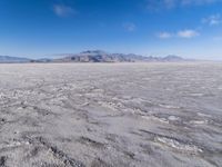 there is a lone motorcycle parked in the desert, with mountains in the background, and no one on the side
