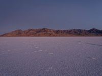 a lone person in the middle of a vast, open area with mountains behind them