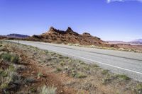 a lone road curves across an arid plain, the mountains in the distance are covered with dirt