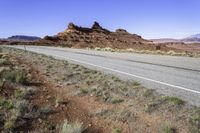 a lone road curves across an arid plain, the mountains in the distance are covered with dirt