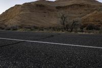 a lone road near the desert mountains with the moon in the sky behind it,