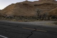 a lone road near the desert mountains with the moon in the sky behind it,