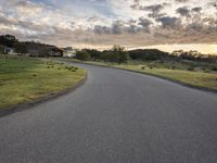 a lone skateboarder rides down an empty road in the sunset light of clouds