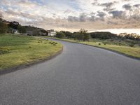 a lone skateboarder rides down an empty road in the sunset light of clouds