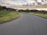 a lone skateboarder rides down an empty road in the sunset light of clouds