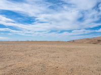 a lone white truck on a barren plain under a partly cloudy sky and clouds of many colors