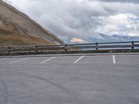 there is a car that is driving in the parking lot alone with the hills in the background