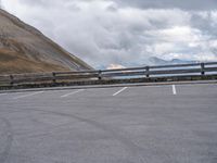 there is a car that is driving in the parking lot alone with the hills in the background