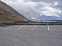 there is a car that is driving in the parking lot alone with the hills in the background