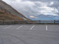 there is a car that is driving in the parking lot alone with the hills in the background