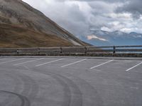 there is a car that is driving in the parking lot alone with the hills in the background