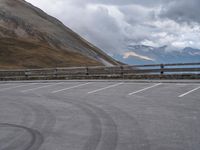 there is a car that is driving in the parking lot alone with the hills in the background