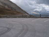 there is a car that is driving in the parking lot alone with the hills in the background