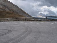 there is a car that is driving in the parking lot alone with the hills in the background