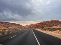 a highway with mountains in the distance and no cars on it while going through the desert