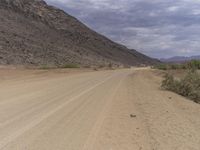 a small vehicle traveling across a barren road between some large rocks and boulders on one side