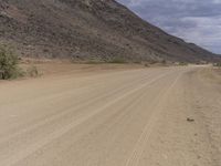 a small vehicle traveling across a barren road between some large rocks and boulders on one side