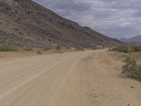 a small vehicle traveling across a barren road between some large rocks and boulders on one side