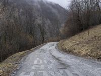 a lonely, empty road in the middle of a hilly area with mountains in the distance