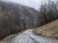 a lonely, empty road in the middle of a hilly area with mountains in the distance