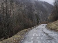 a lonely, empty road in the middle of a hilly area with mountains in the distance