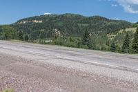 a lone skateboarder is sitting alone on the street in front of the mountains