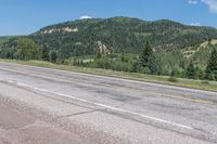 a lone skateboarder is sitting alone on the street in front of the mountains