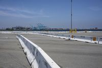 a stop sign is in a concrete parking lot with a barge port and a clear blue sky