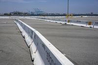 a stop sign is in a concrete parking lot with a barge port and a clear blue sky