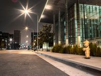 a yellow fire hydrant is located by the street at night on a sidewalk near a tall building