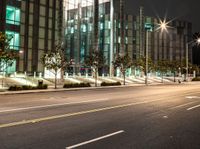 a empty street near large buildings at night time that appears to be driving on the road