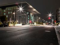 a city street has lights shining brightly on the sides of buildings at night time,