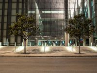 the outside of an office building lit up at night with trees in front of it