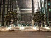 the outside of an office building lit up at night with trees in front of it