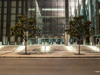 the outside of an office building lit up at night with trees in front of it