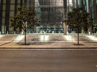 the outside of an office building lit up at night with trees in front of it