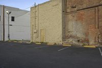 the parking lot at this old warehouse has parked cars and a fire hydrant in the middle of it