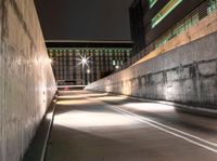 there is a car on the road going down the tunnel at night time under the street light