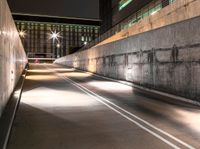 there is a car on the road going down the tunnel at night time under the street light