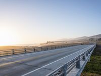 a long bridge spans over the pacific ocean near a sandy beach with a small town in the background