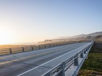 a long bridge spans over the pacific ocean near a sandy beach with a small town in the background