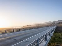 a long bridge spans over the pacific ocean near a sandy beach with a small town in the background