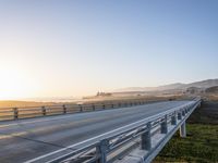 a long bridge spans over the pacific ocean near a sandy beach with a small town in the background