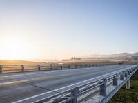 a long bridge spans over the pacific ocean near a sandy beach with a small town in the background