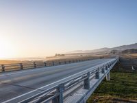 a long bridge spans over the pacific ocean near a sandy beach with a small town in the background